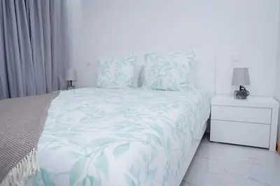 a white bedroom with a bed and a night stand at Saw Paradise in Praia T2 in Praia