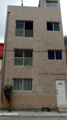 a tall brick building with windows and a white door at Repousando II in Ribeira Grande