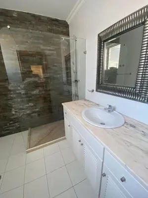a bathroom with a sink and a shower with a mirror at Vivenda com pátio, no coração do Mindelo in Mindelo
