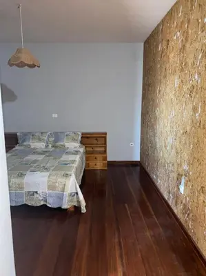 a bedroom with a bed and a stone wall at Vivenda com pátio, no coração do Mindelo in Mindelo