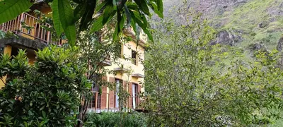 a building in front of a mountain with trees at Casa Cavoquinho in Paul