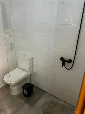 a white bathroom with a toilet and a shower at Pensão Gonçalves in Calheta de São Miguel