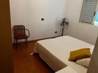 a bedroom with a bed and a fan and a chair at Beira Mar AB2 in Santa Maria