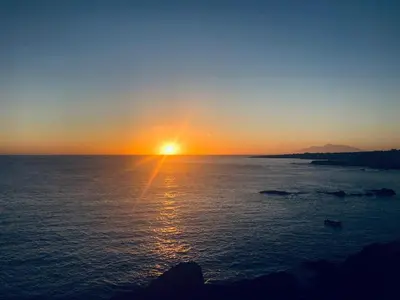 a sunset over the ocean with the sun setting at Get house kira in Cidade Velha