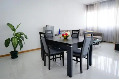 a dining room with a black table and chairs at Apartamento das Flores 2 in Praia