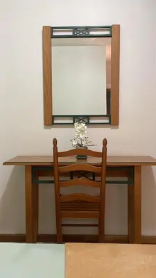 a dressing table with a mirror and a wooden chair at Felicidade Hotel in Praia