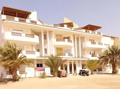 a large white building with palm trees in front of it at Apartment in Sal Rei - Boa Vista in Sal Rei