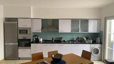 a kitchen with white cabinets and a wooden table with a tableablish at Vila Verde - Chez Val in Santa Maria