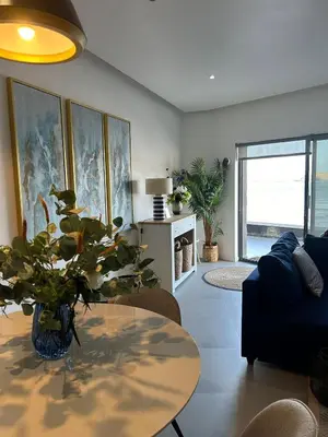 a living room with a table and a blue couch at Ely's Place by the Sea in Praia Baixo