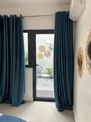 a room with blue curtains and a sliding glass door at Ely's Place by the Sea in Praia Baixo