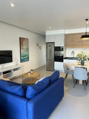 a living room with a blue couch and a kitchen at Ely's Place by the Sea in Praia Baixo