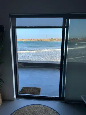 a view of the ocean through a sliding glass door at Ely's Place by the Sea in Praia Baixo