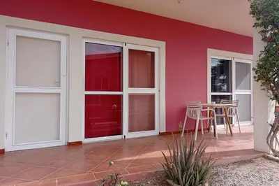 a patio with a table and chairs and a red wall at Appartamento Ferreira Stella Maris Exclusive in Calheta Do Maio