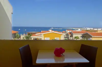 a white table with a red flower on top of it at Appartamento Polvo. Stella Maris Exclusive in Calheta Do Maio