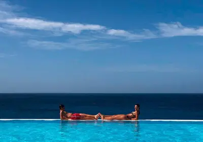 a man and woman laying in a swimming pool near the ocean at Appartamento Percebes. Stella Maris Exclusive in Calheta Do Maio