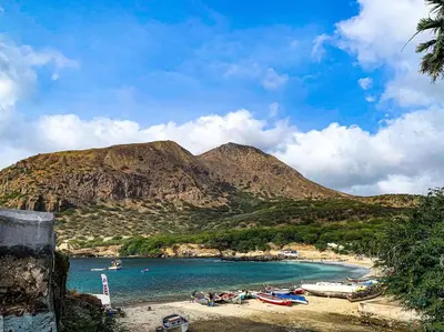 a group of boats on a beach with a mountain at Kaza Papaya - Papaya House in Tarrafal