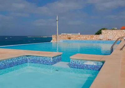a large swimming pool with blue water and the ocean at Villa Baleia Stella Maris Exclusive in Calheta Do Maio