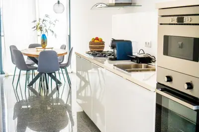 a white kitchen with a table and a sink at Morabezahome - Zaza in Mindelo
