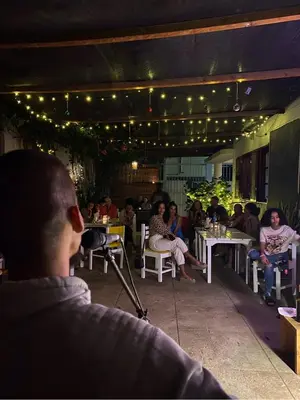 a group of people sitting at tables in a restaurant at Syd's Guesthouse in Praia