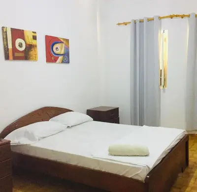 a bedroom with a large bed with a white bedspread at Muralha Rooms in Mindelo