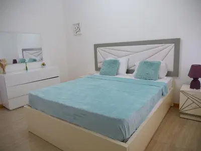 a white bedroom with a large bed with blue sheets at wonder of the archipelago in Praia