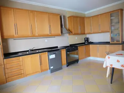 a large kitchen with wooden cabinets and a table at wonder of the archipelago in Praia