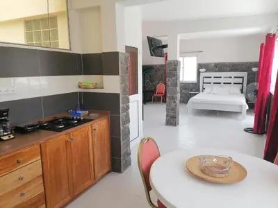 a kitchen with a table and a room with a bed at STUDIO VUE MER - CASA da LUZ in Mindelo