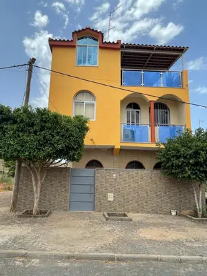 a yellow house with a fence in front of it at Casa Mendes- Quarto individual in Praia