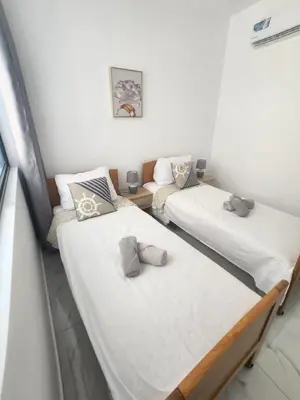 two twin beds in a room with white walls at Boa Mindelo City in Mindelo