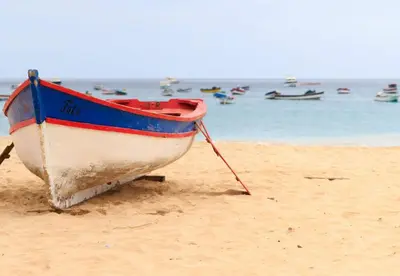 a boat sitting on a beach with the ocean in the background at Time Out DjadSal Residence AC Wifi in Santa Maria