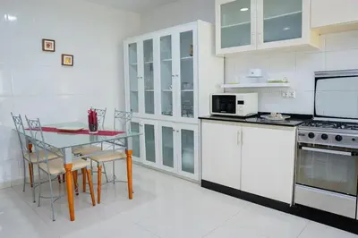 a kitchen with white cabinets and a table with chairs at Nice And Modern with king size bed in Praia