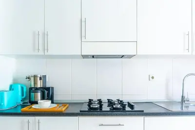 a kitchen with white cabinets and a stove top oven at Bliss Apartments - T2 Nicole in Mindelo