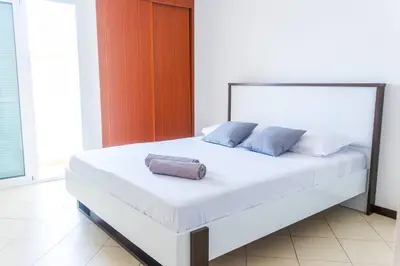 a white bed with a towel on it in a room at Bliss Apartments - T2 Nicole in Mindelo