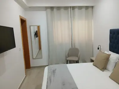 a bedroom with a bed and a chair and a mirror at Charming House Tarrafal in Tarrafal