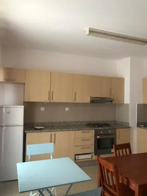 a kitchen with wooden cabinets and a table and a dining room at Apartamento Oiá Mindelo in Mindelo