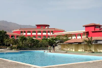 a resort with a pool in front of a red building at Hotel Santantao Art Resort in Porto Novo