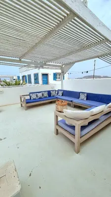 a patio with blue couches and chairs under an umbrella at Surf House Casa Vehla in Sal Rei