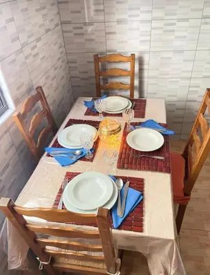 a dining room table with white plates and blue napkins at 1 chambre proche aeroporto cabo verde in Espargos