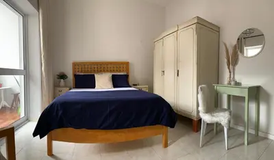 a bedroom with a bed and a cabinet and a chair at Flat Mindelo 30 in Mindelo