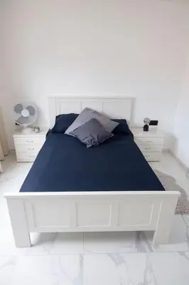 a white bedroom with a white bed with blue sheets at Bliss Apartments T2 - Julia in Mindelo