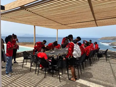 a group of people in red shirts sitting at a table at Cabo Verde Beach Sport Resort in Porto Novo