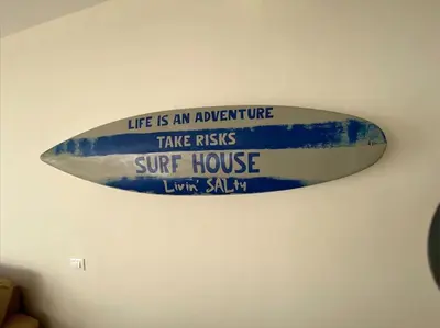 a surfboard on a wall with a sign on it at Surf House - Your Exclusive Getaway in Palmeira