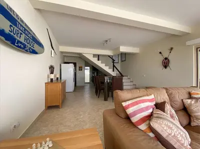 a living room with a couch and a dining room at Surf House - Your Exclusive Getaway in Palmeira
