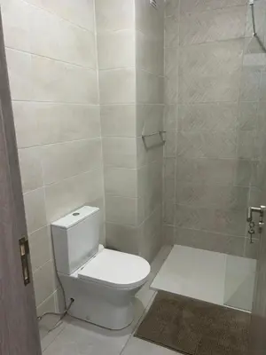 a bathroom with a white toilet and a shower at Laginha Views in Mindelo