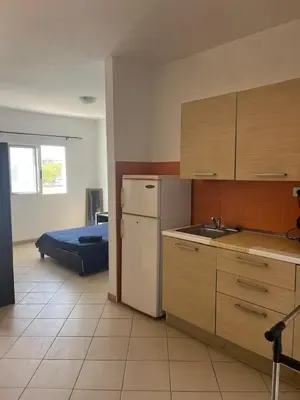 a kitchen with a refrigerator and a sink and a bed at Central Studio Apartment near beach in Santa Maria