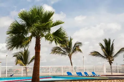 a swimming pool with palm trees and blue chairs at Murdeira Village in Beirona