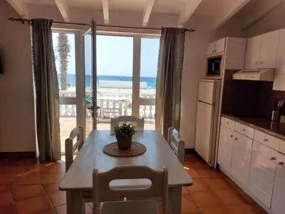 a kitchen with a table with chairs and a view of the ocean at Vista Mar - Seafront Holiday Apartments in Santa Maria