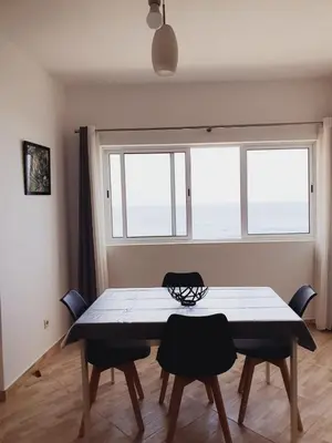 a dining room with a table and two windows at Residencia Solimar in Ponta do Sol