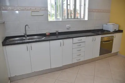 a kitchen with white cabinets and a sink at Hotel Cantinho in Montanha