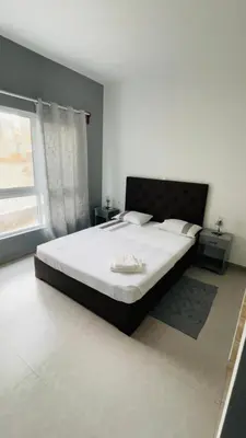 a bedroom with a large bed with white sheets and a window at Hostel Rocha Marisol in Ponta do Sol